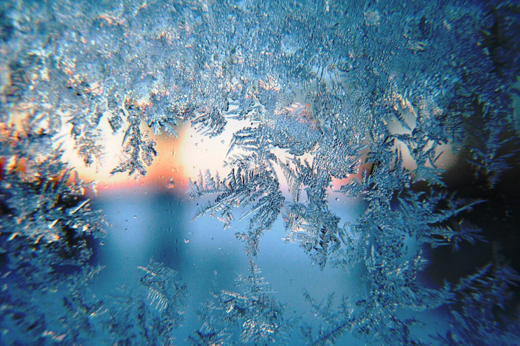 Ice crystals on frozen glass and background in hues of turquoise