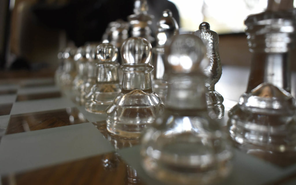 Glass and wood chessboard with close up of glass chess pieces