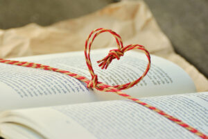 Open book with a string heart of red and yellow twine