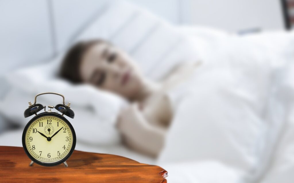 Clock on nightstand with Woman waking up and looking at it.
