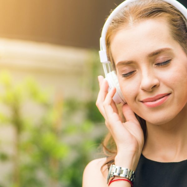 Woman smiling with eyes closed with earphones on. Listening to courses is relaxing and uplifting!