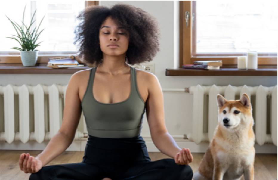 Woman meditating in traditional pose with cute dog.
