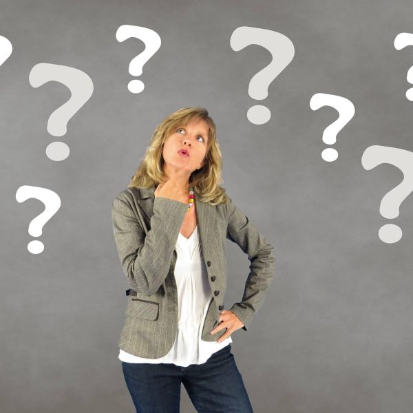 Woman surrounded by question marks indicating uncertainty and not being sure. Overcome uncertainty and fear with a Mind Belief course!