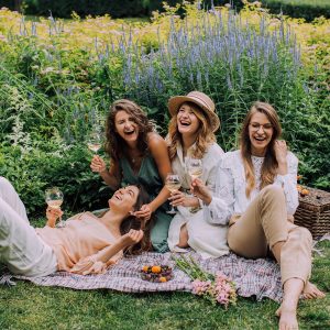 Group of joyful, laughing, woman on a blanket in a field of lavender. Bring on your joy, prosperity and abundance with Mind Truths courses!