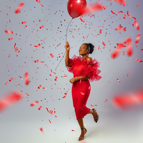 Woman dancing with big red balloon and confetti in a party atmosphere. Release your fears and activate your power with Mind Truths courses!