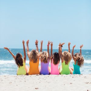 Happy, joyous ladies in bright-colored bathing suits on a gorgeous beach. Be unstoppable, believe in you with our Mind Truths courses!