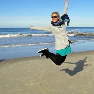 A joyous, excited, enthusiastic woman on a sunny beach. Create a sunny, vibrant enthusiasm with Mind Beliefs, Blossom with Your Greatest Asset, Sunny Enthusiasm!