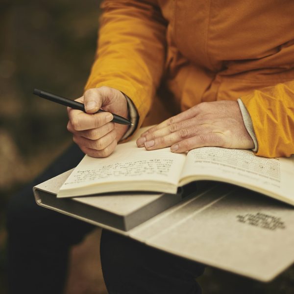 A man writing thoughts in a private journal. Let journaling help you become more aware with Mind Thoughts journal courses!