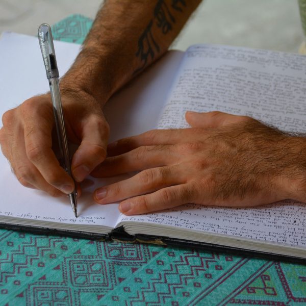 A man spending time writing his thoughts into a journal. Explore journaling, reflection, and self-growth with Mind Thoughts courses!