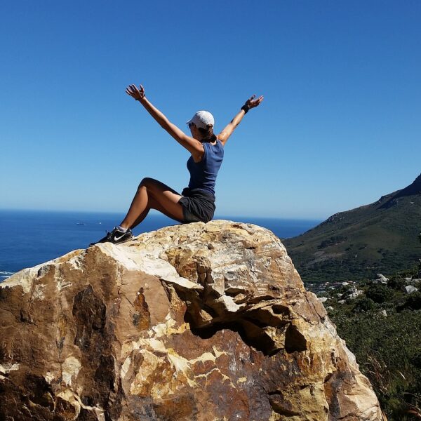 Woman on rock embracing her power with a view over the ocean. Leap into your Fears!
